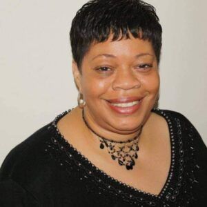 Sharon Lockridge Individual in black top and black necklace smiling .