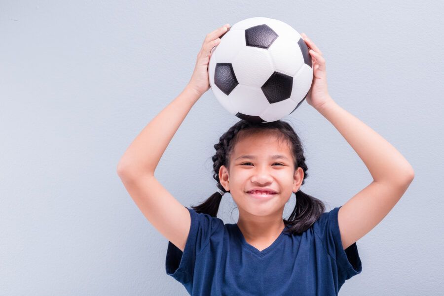 Happy,Child,Girl,Smiling,To,Camera,With,A,Football,On